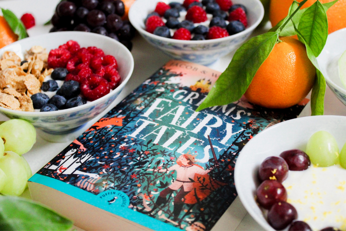 Grim's Fairy Tales book on table with fruits and berries